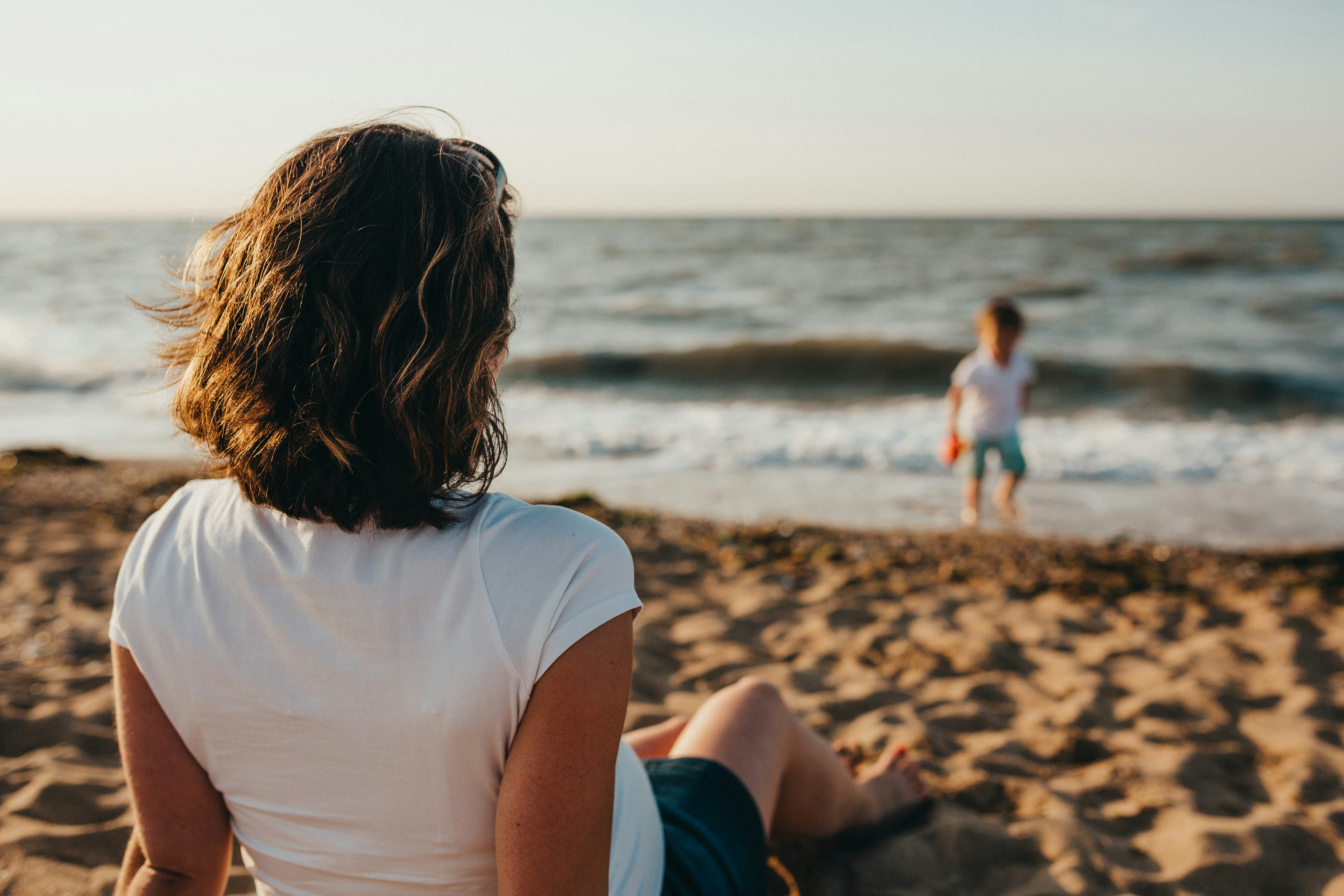 woman on shoreline watching child symbolizing the growth from child to adult and the tranquility neccessary to whether all changes in life. Sarah Haugh, LMHC