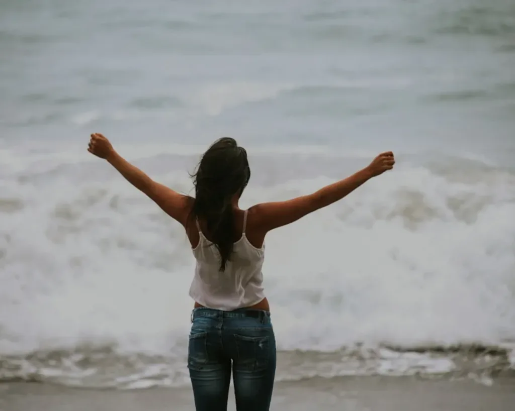 woman on beach who completed anxiety therapy or trauma therapy who is happy and empowered